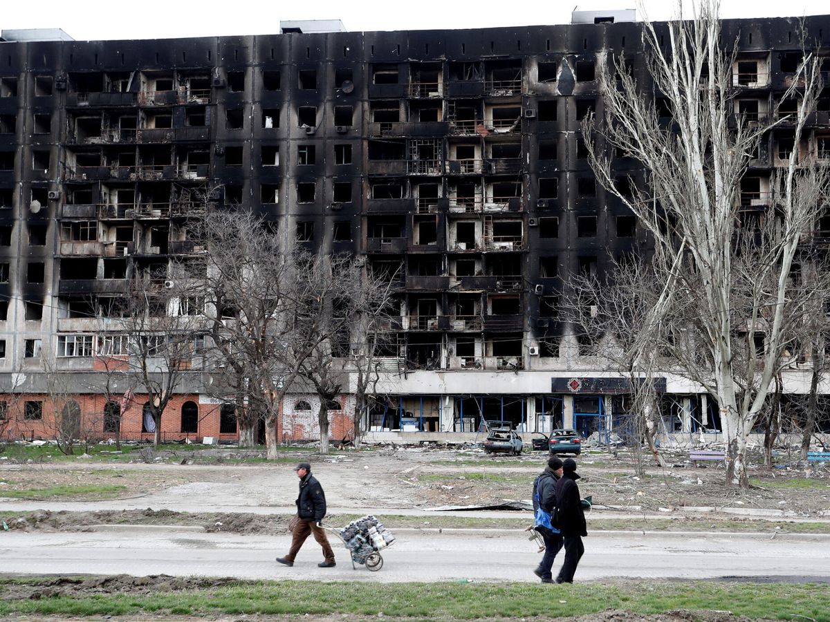 Foto: Residentes locales pasan por delante de un edificio quemado durante el conflicto entre Ucrania y Rusia en Mariúpol. (Reuters/Alexander Ermochenko)