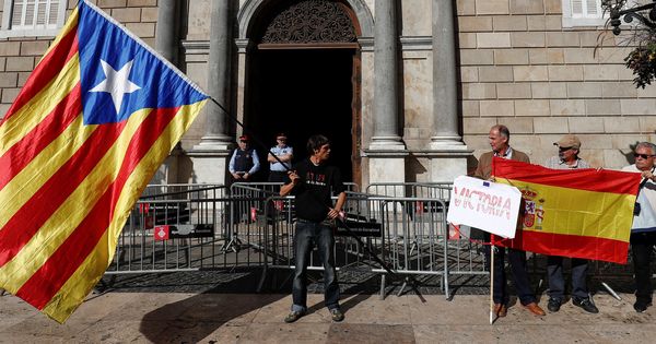 Foto: Un joven ondea una bandera independentista junto a un grupo de hombres con una bandera de España a las puertas del Palau de la Generalitat. (Reuters)