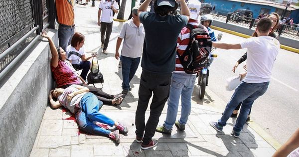 Foto: Dos mujeres yacen en el suelo durante un enfrentamiento entre un grupo de personas adeptas al oficialismo y personas opositoras al gobierno nacional. (EFE)