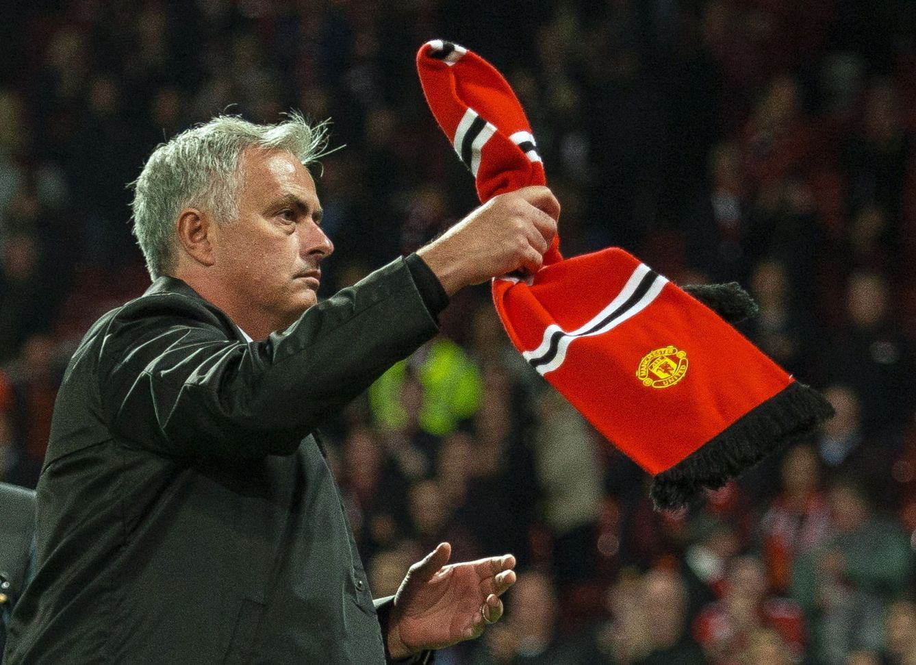 Mourinho recoge una bufanda que le tiraron tras el partido. (EFE)