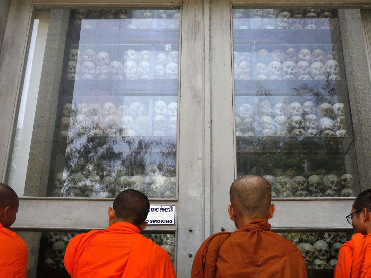 Monjes budistas observan los cráneos de víctimas encontrados en el área de exterminio de Choeung Ek, hoy convertido en un memorial del genocidio a las afueras de Phnom Penh. (Reuters)
