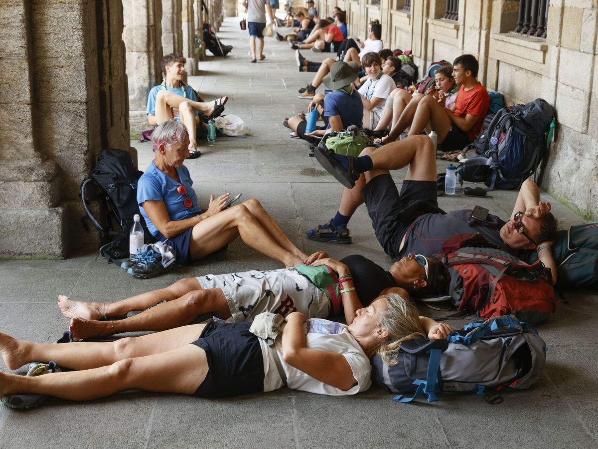 Foto: Un grupo de peregrinos descansa en los bajos del Palacio de Raxoy, en la plaza del Obradoiro (Santiago de Compostela). (EFE)