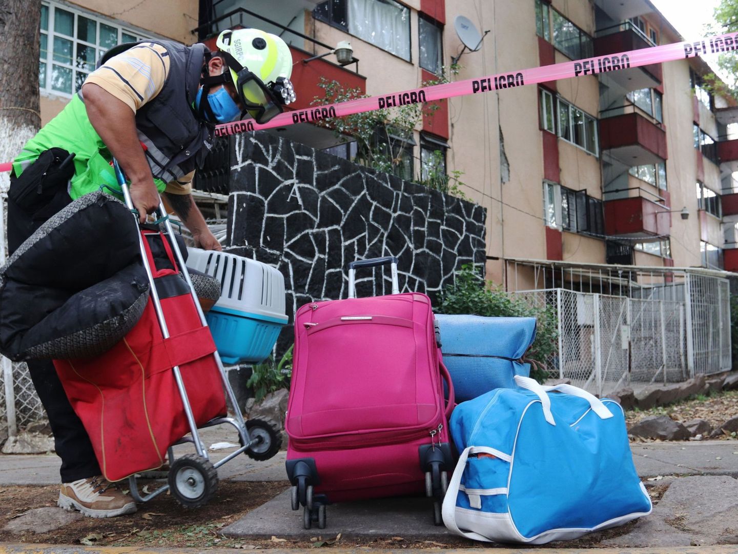 Un trabajador de Protección Civil ayuda con sus pertenencias a habitantes de un edifico dañado después del sismo en la Ciudad de México (México) (EFE)