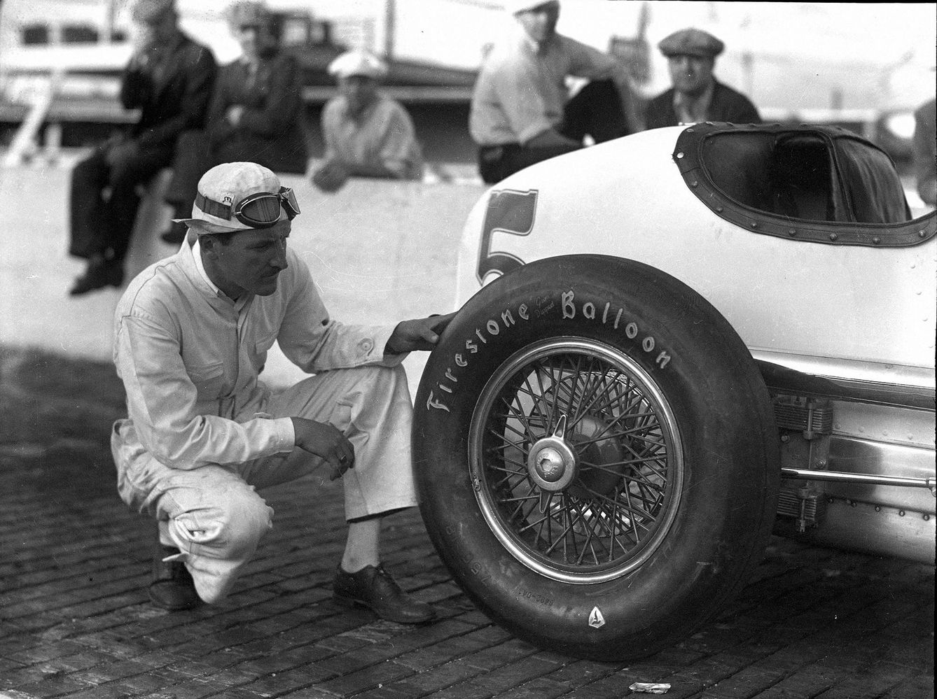 Un piloto revisando los neumáticos de su coche de competición.