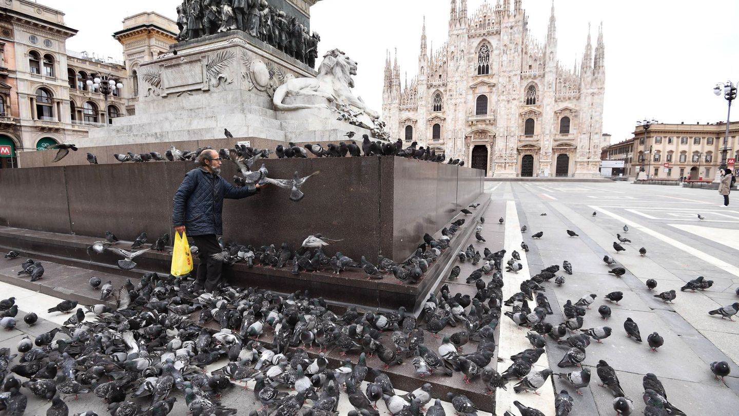 Un hombre da de comer a las palomas en la Piazza del Duomo de Milán (EFE)