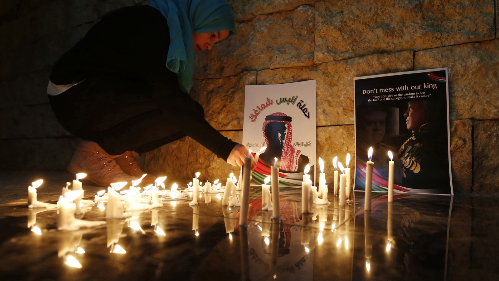 Foto: Una jordana enciende una velas cerca de una foto del piloto jordano ejecutado por el ISIS, Muath al-Kasasbeh, en Amman. (Reuters)