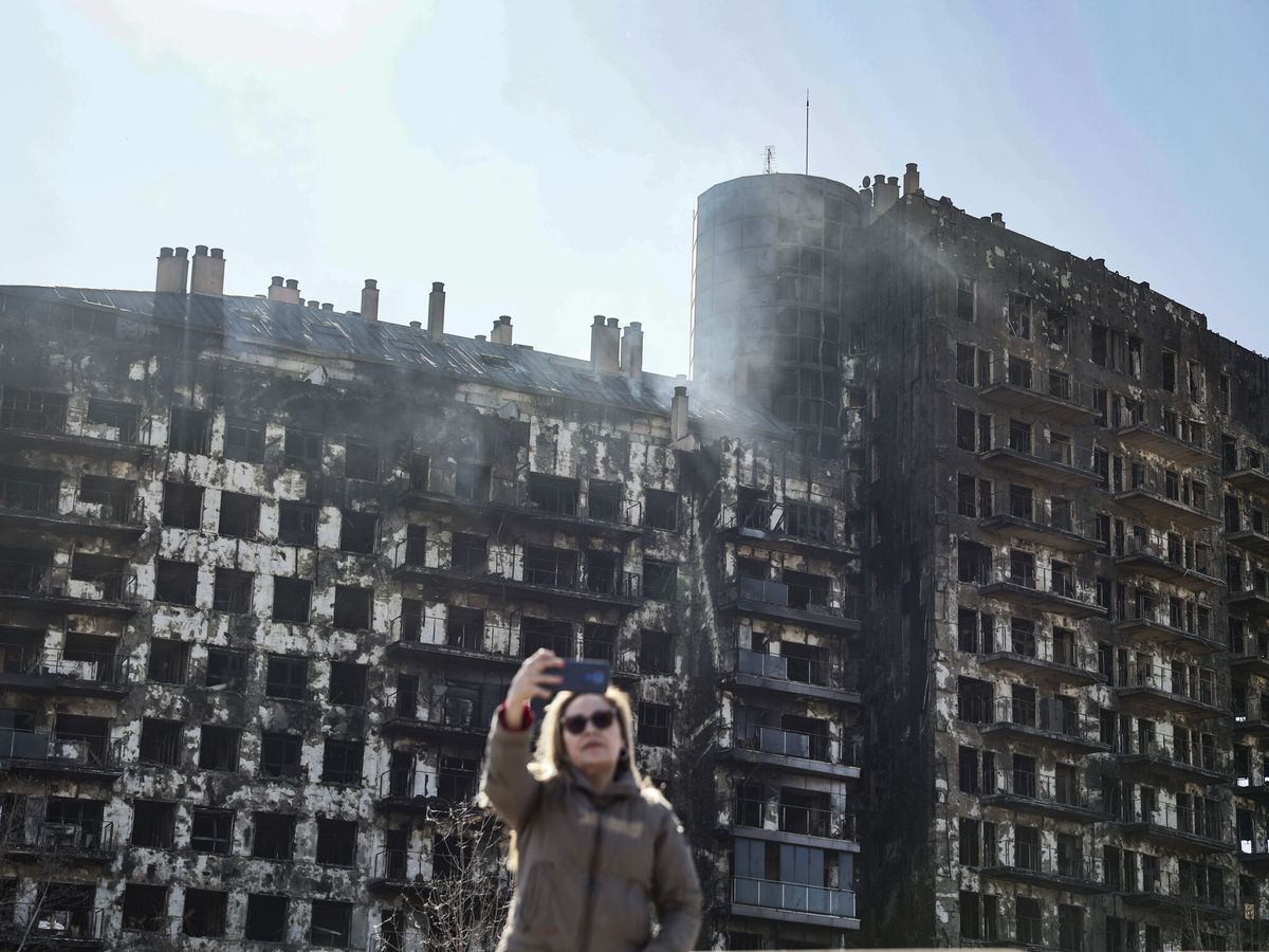 Foto: En la imagen una mujer se toma una fotografía ante el edificio incendiado. (EFE/Biel Aliño)