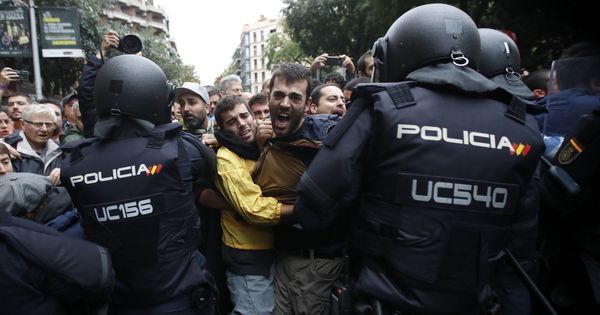 Foto: Agentes antidisturbios de la Policía Nacional forman un cordón de seguridad frente al colegio Ramón Llull de Barcelona el 1-O. (EFE)