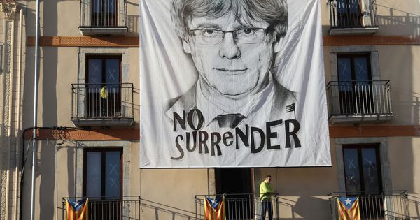 Foto: Un hombre coloca una pancarta del expresidente de la Generalitat de Cataluña Carles Puigdemont en Barcelona. (Reuters)