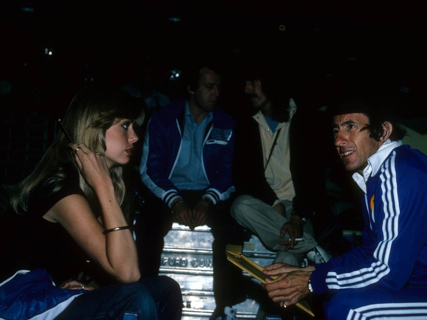 Gran Premio de Mónaco de 1978. En primer plano, Jackie Stewart conversa con una mujer. Al fondo, entre la oscuridad, charlan George Harrison (d) y Jackie Oliver (i). (Imago)