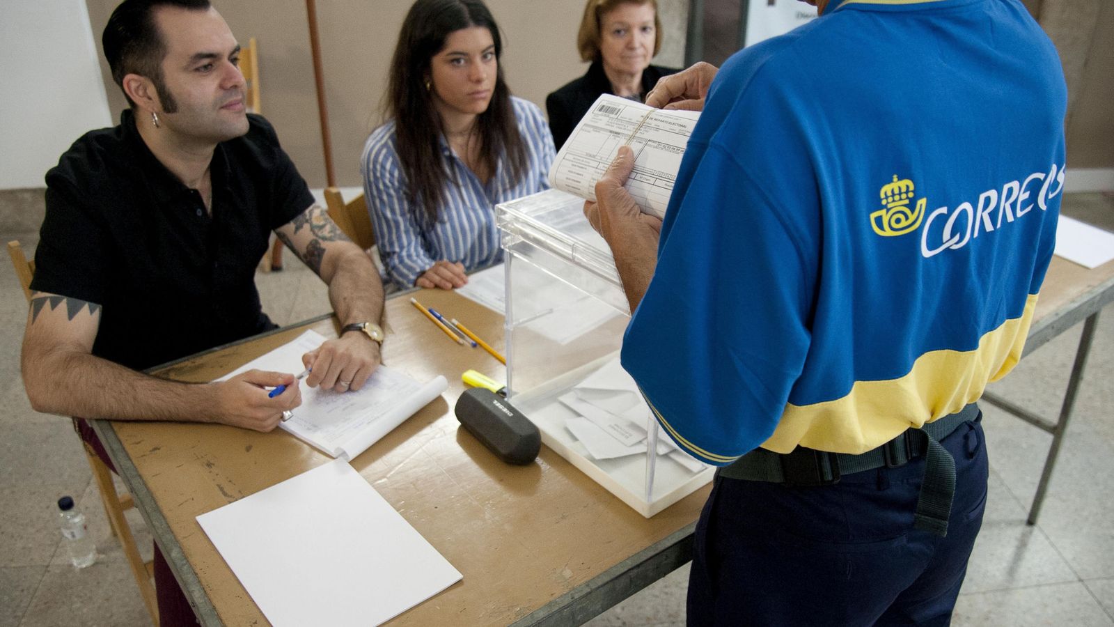 Foto: Un funcionario de Correos entrega en una mesa electoral varios votos por correo. (EFE) 