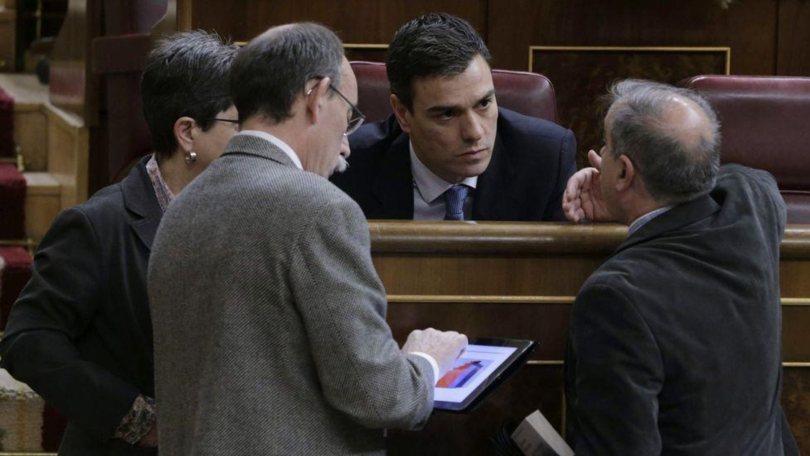 Foto: El líder del PSOE, Pedro Sánchez, conversa con un grupo de diputados mientras uno de ellos observa su iPad. (EFE)