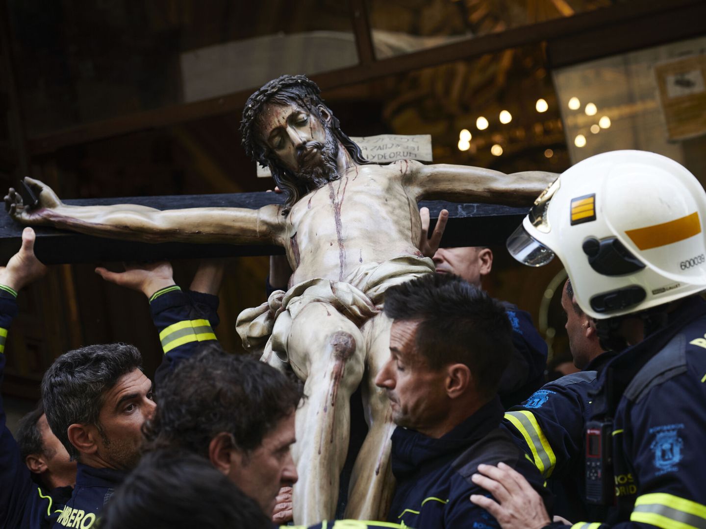 Varios bomberos sacan la talla de El Cristo de los Niños de la Iglesia de San Antón de Madrid. (EFE/Luca Piergiovanni)