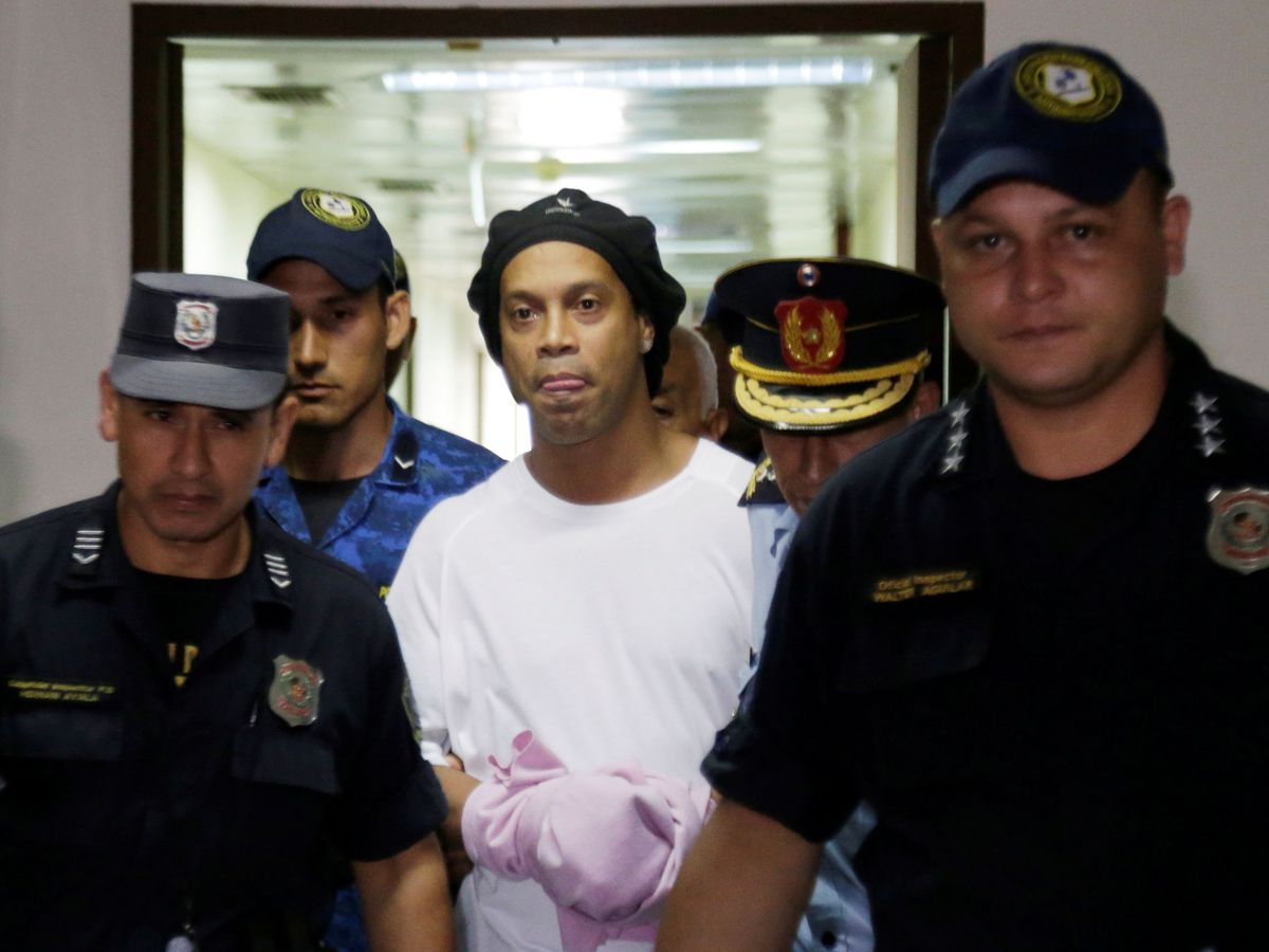 Foto: Ronaldinho, esposado y escoltado por la policía al interior de su celda en Paraguay. (Reuters)