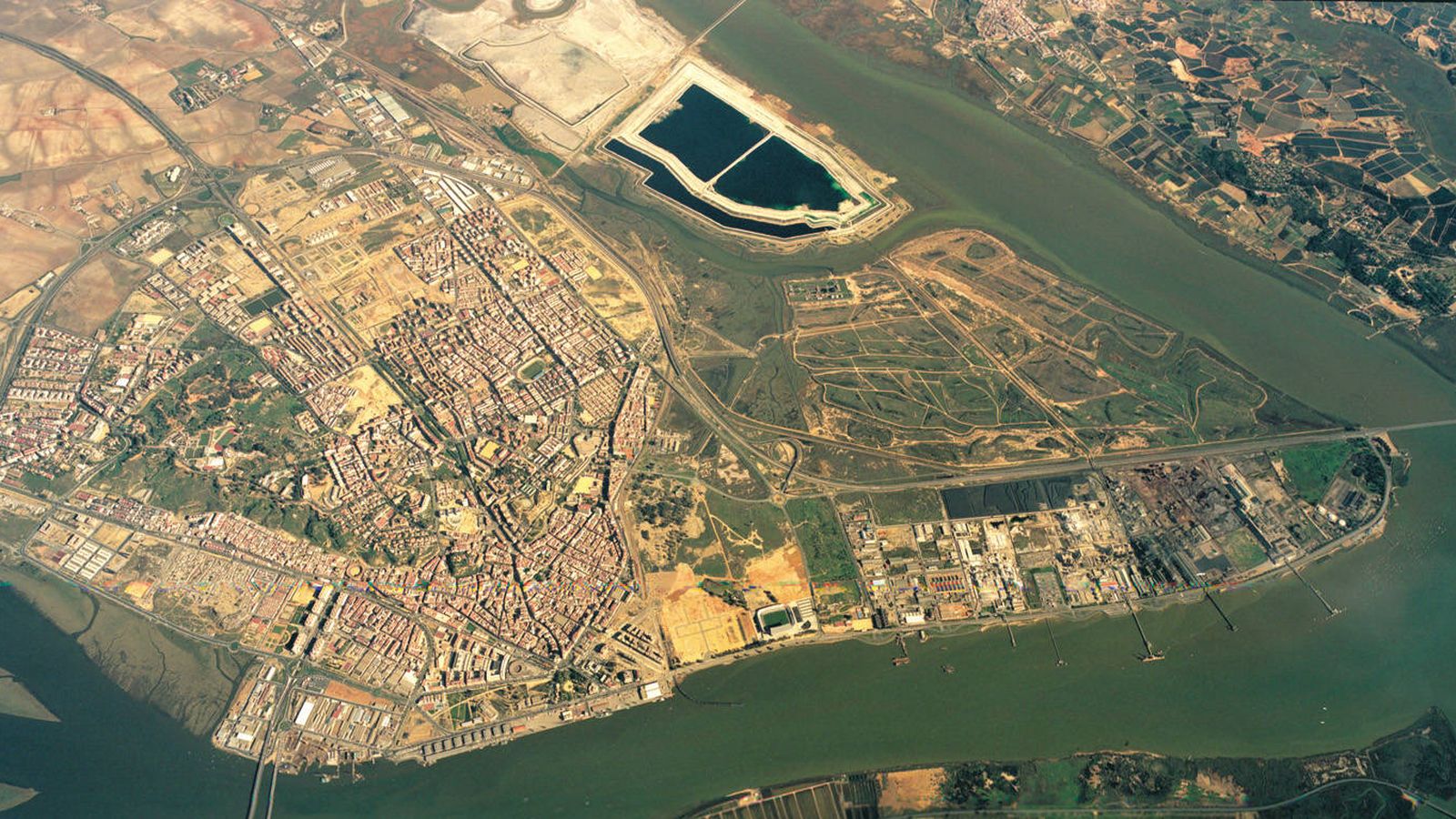 Foto: Imagen aérea de Huelva con las balsas de fosfoyesos en la parte superior. (Aiqbe)