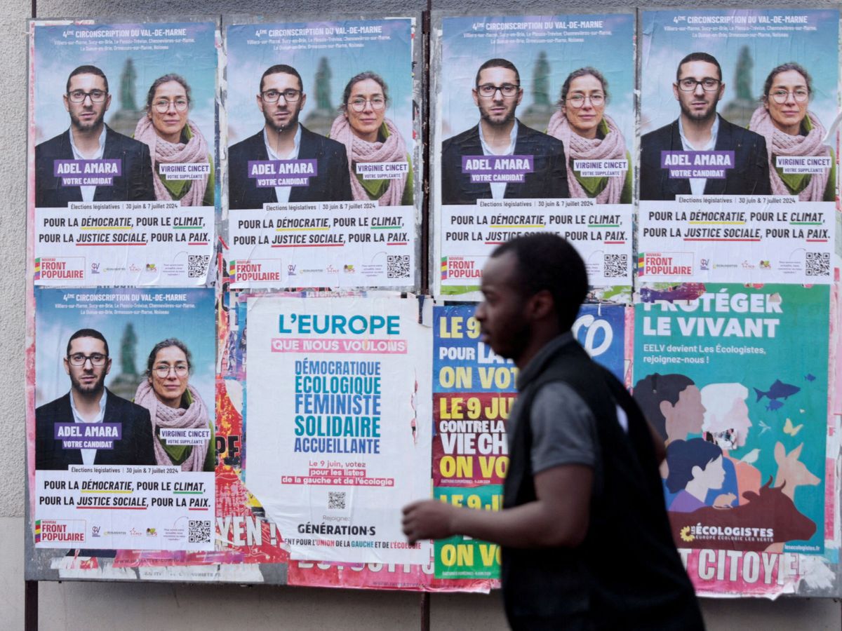 Foto: Un hombre pasa por varios carteles electorales de izquierdas en Francia. (Reuters/Abdul Saboor)