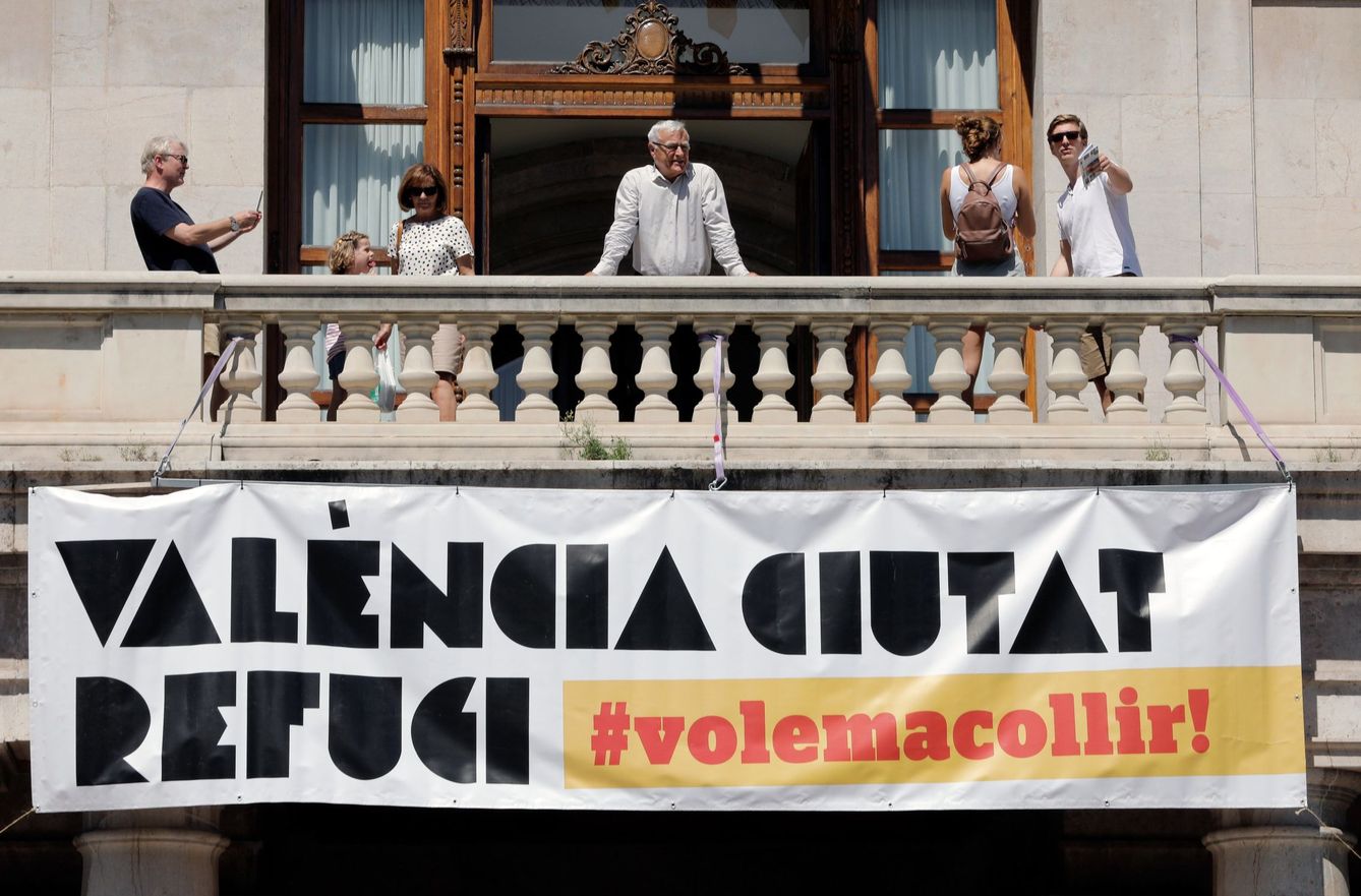 El alcalde de València, Joan Ribó, se asoma al balcón de la Plaza del Ayuntamiento tras la instalación de una gran pancarta con el lema 'Valencia, ciudad refugio'. (EFE)