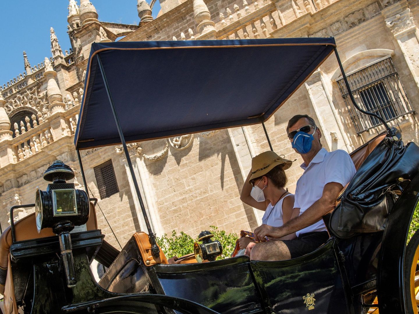 Turistas en coche de caballos en los alrededores de la Catedral de Sevilla, el pasado junio. (EFE)