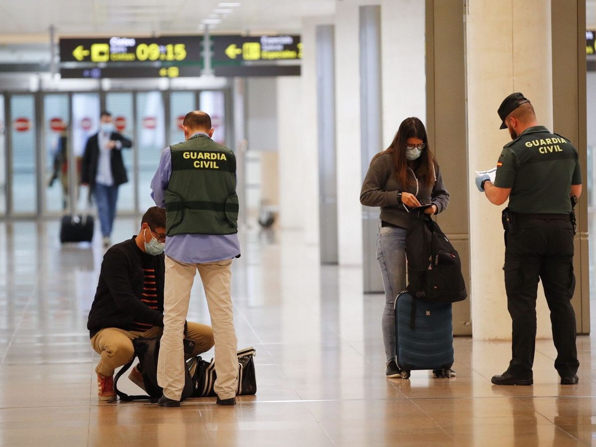 Foto: Agentes de la Guardia Civil realizan un control a unos viajeros en el aeropuerto de El Prat. (EFE/Alejandro García)