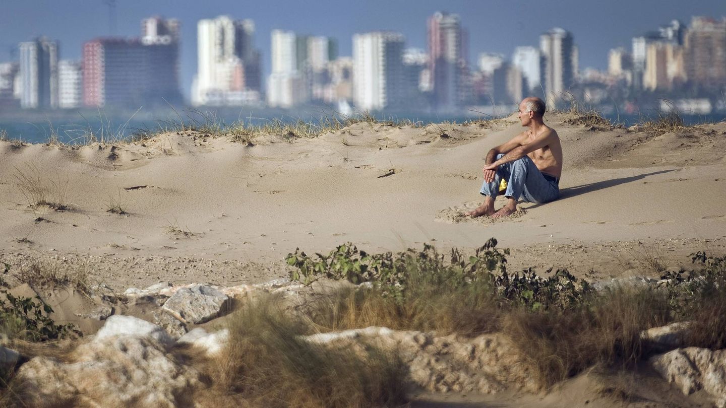 Un hombre disfruta de la playa de la Patacona, en Valencia, con los edificios de la ciudad al fondo. (EFE)