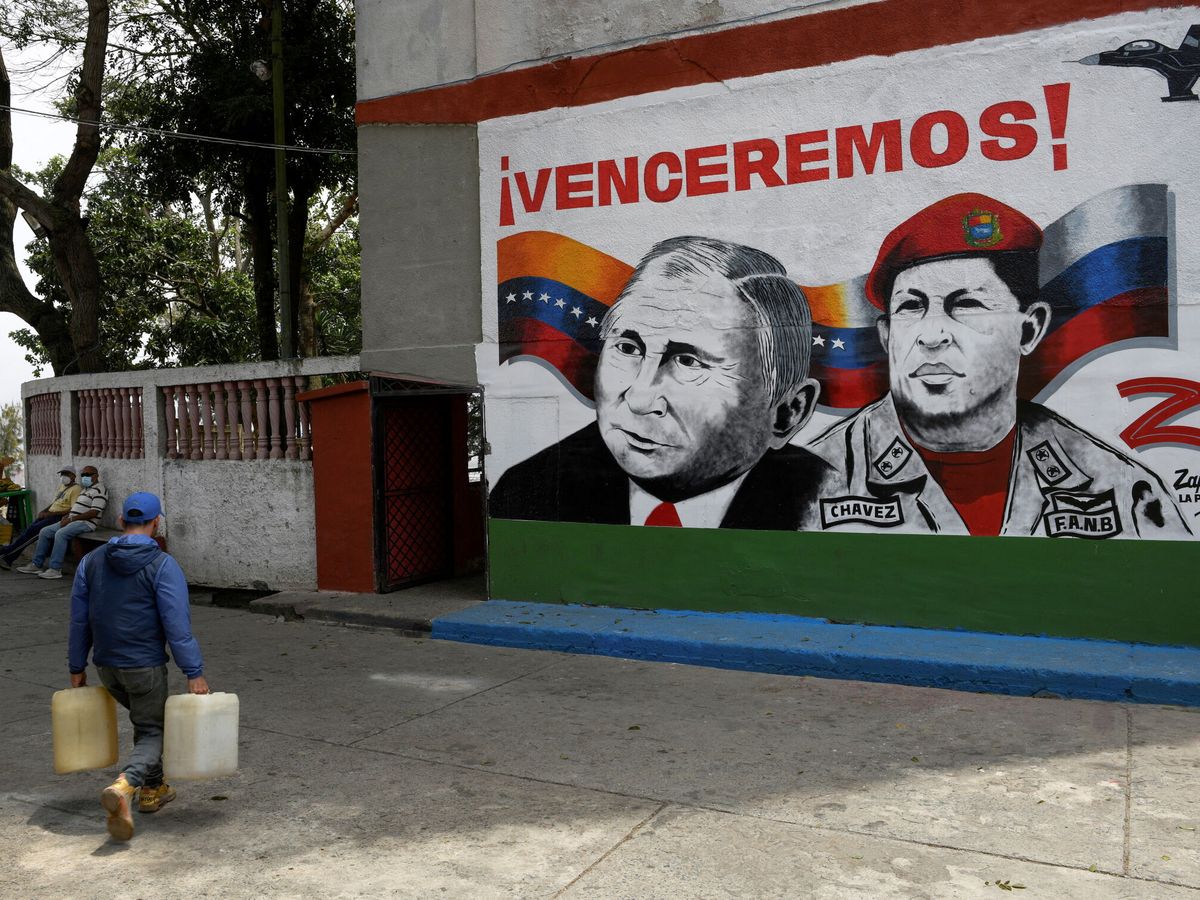 Foto: Un hombre camina frente a un mural con los rostros de Vladímir Putin y Hugo Chávez en Caracas. (Reuters/Gaby Oraa)