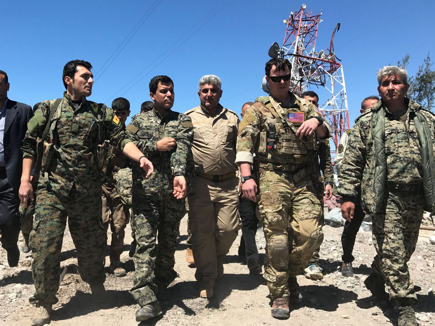 Un oficial de EEUU camina con combatientes kurdos de las YPG cerca de Malikiya, Siria. (Reuters)