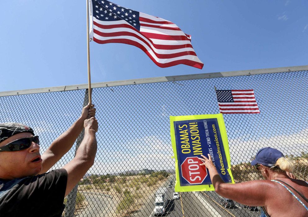Foto: Dos estadounidenses contrarios a la entrada de inmigrantes protestan sobre una autopista en Murrieta, California. (Reuters)