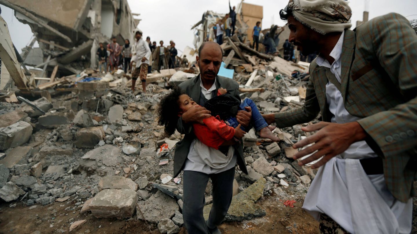 Un hombre socorre a una niña tras un bombardeo saudí en Saná, Yemen. (Reuters)