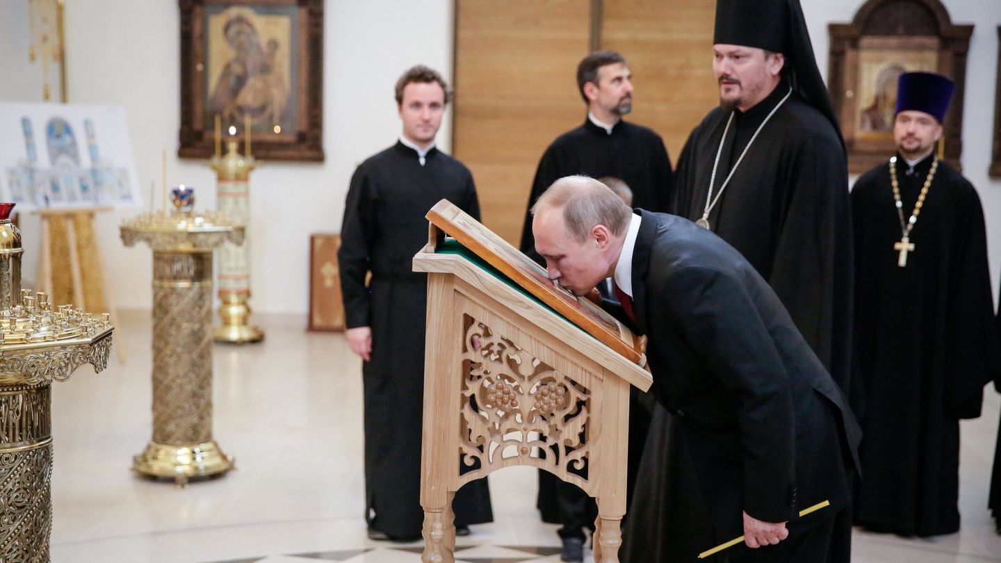 Vladimir Putin besa una imagen que representa la Santísima Trinidad junto al representante del patriarca de Moscú en París, Obispo Néstor. (EFE)