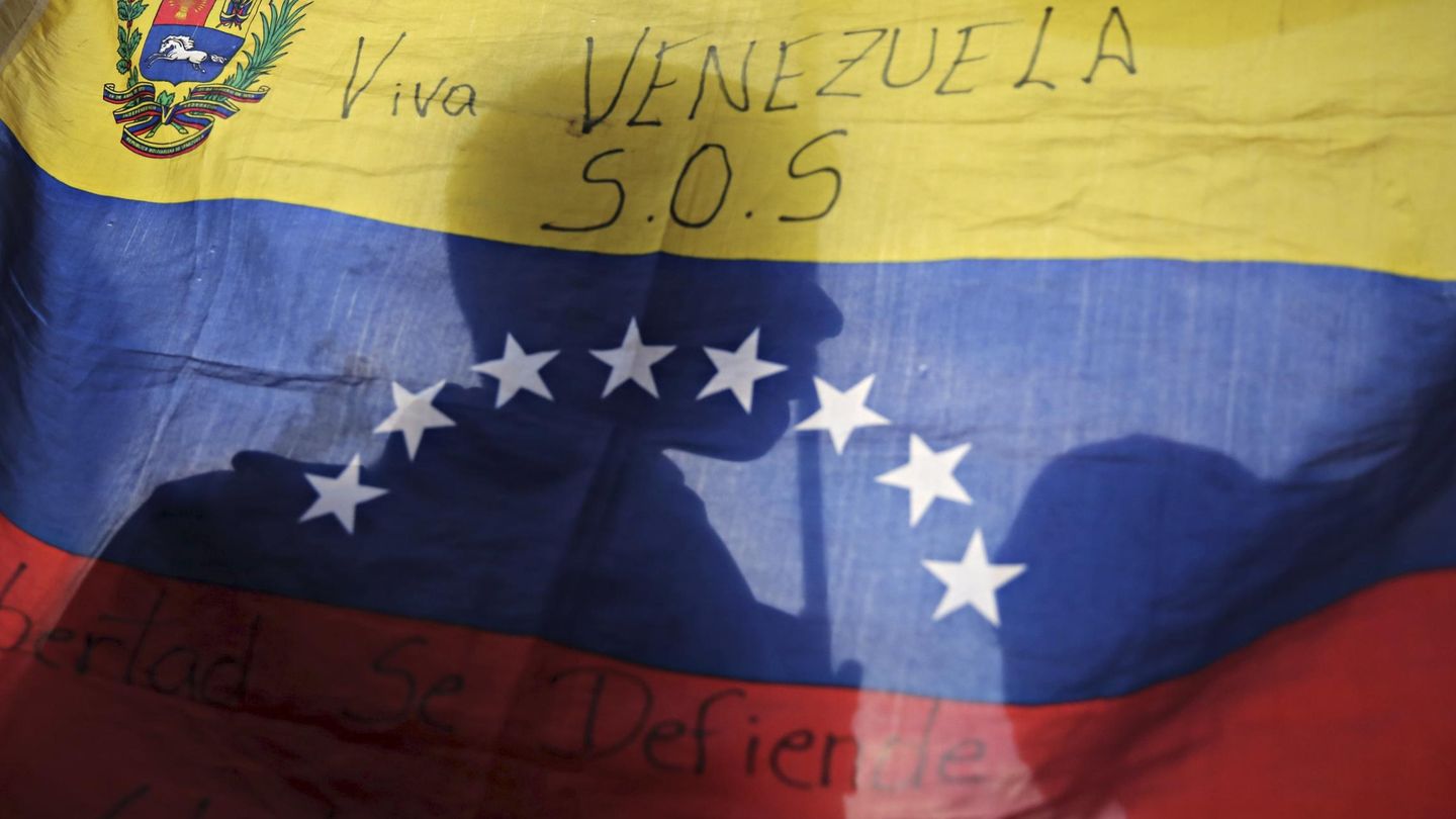 La silueta de un opositor a través de una bandera venezolana durante un mitin electoral en Caracas (Reuters).