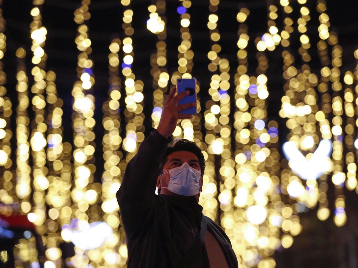 Foto: Un transeúnte se fotografía con las luces de Navidad del centro de Barcelona. (EFE)