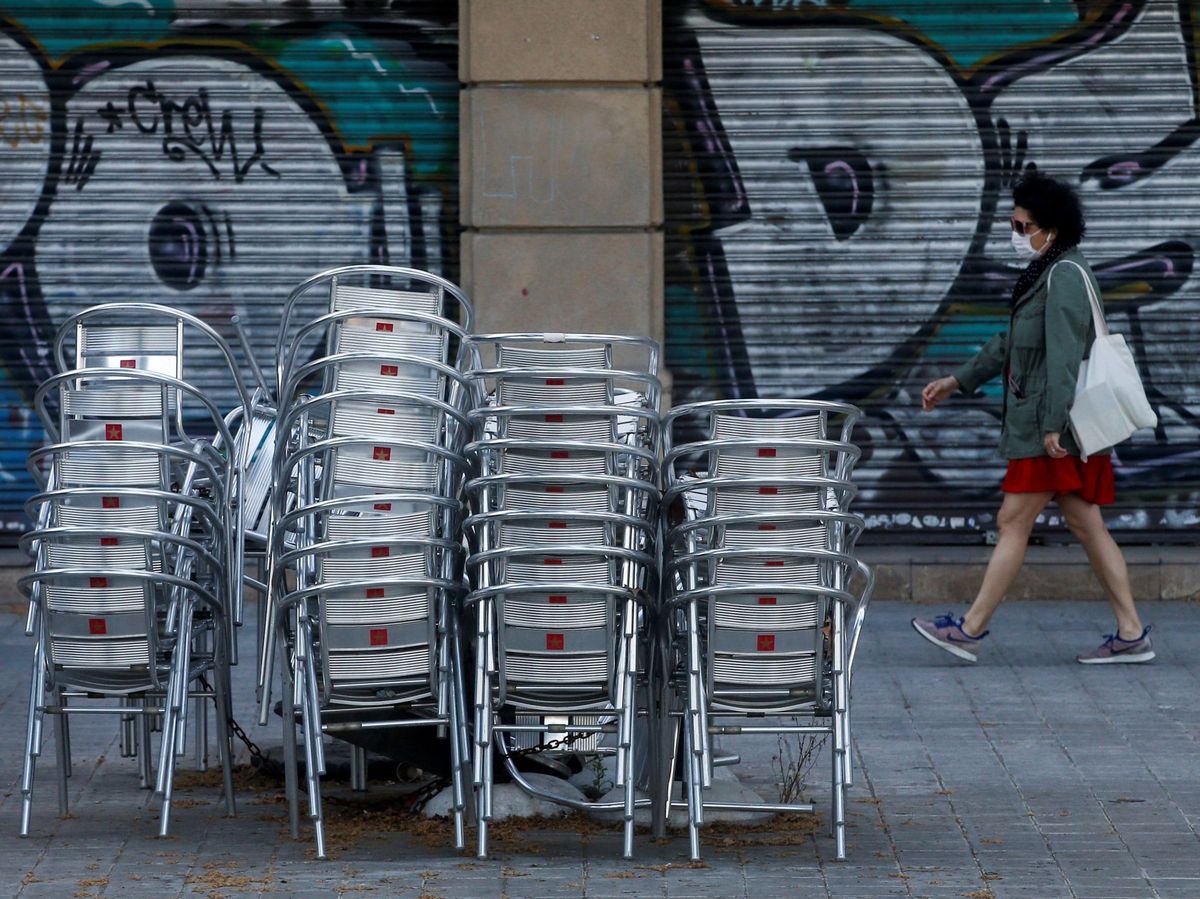 Foto: Una mujer camina cerca de la terraza de un restaurante cerrado de Barcelona (EFE)