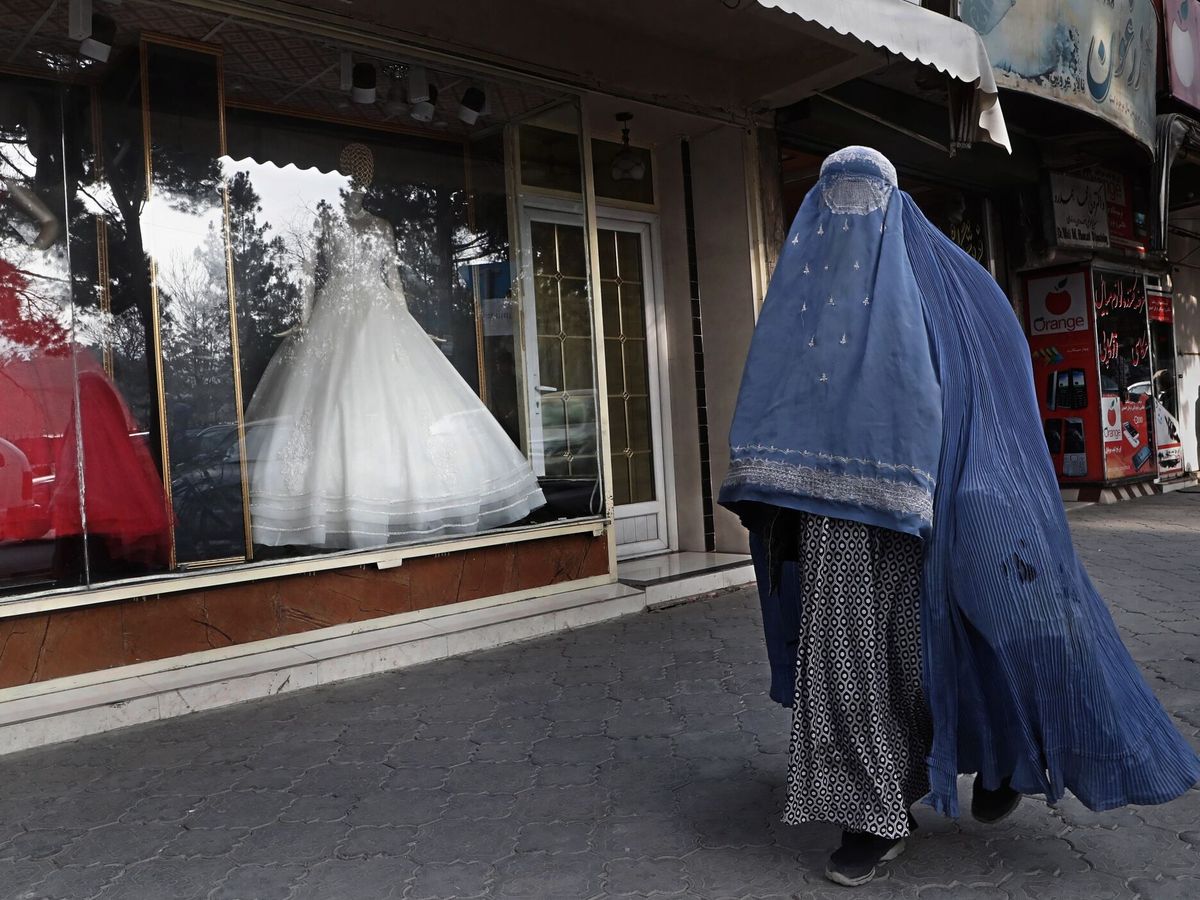 Foto: Una mujer afgana con burka frente a una tienda de vestidos de novia en Kabul, Afganistán. (EFE/Maxim Shipenkov)