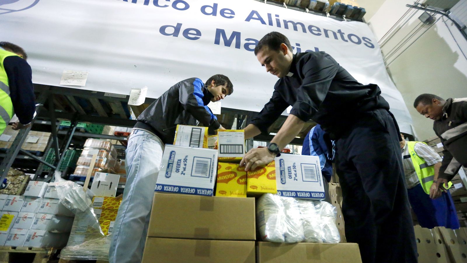 Foto: Un sacerdote acompañado de varios voluntarios trabaja en la fundación Banco de Alimentos de Madrid. (Efe)