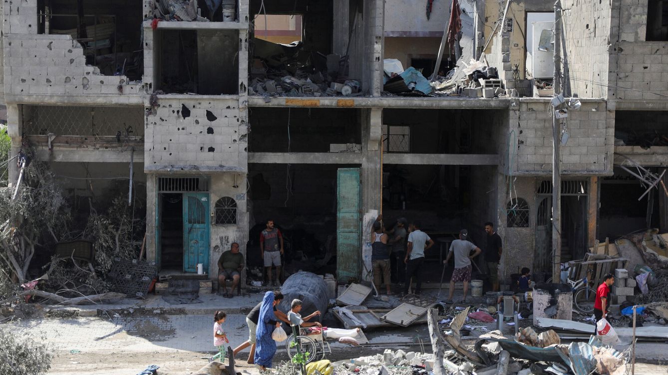 Foto: Un grupo de gazatíes ante los escombros en Gaza. (Reuters/Abed Khaled)