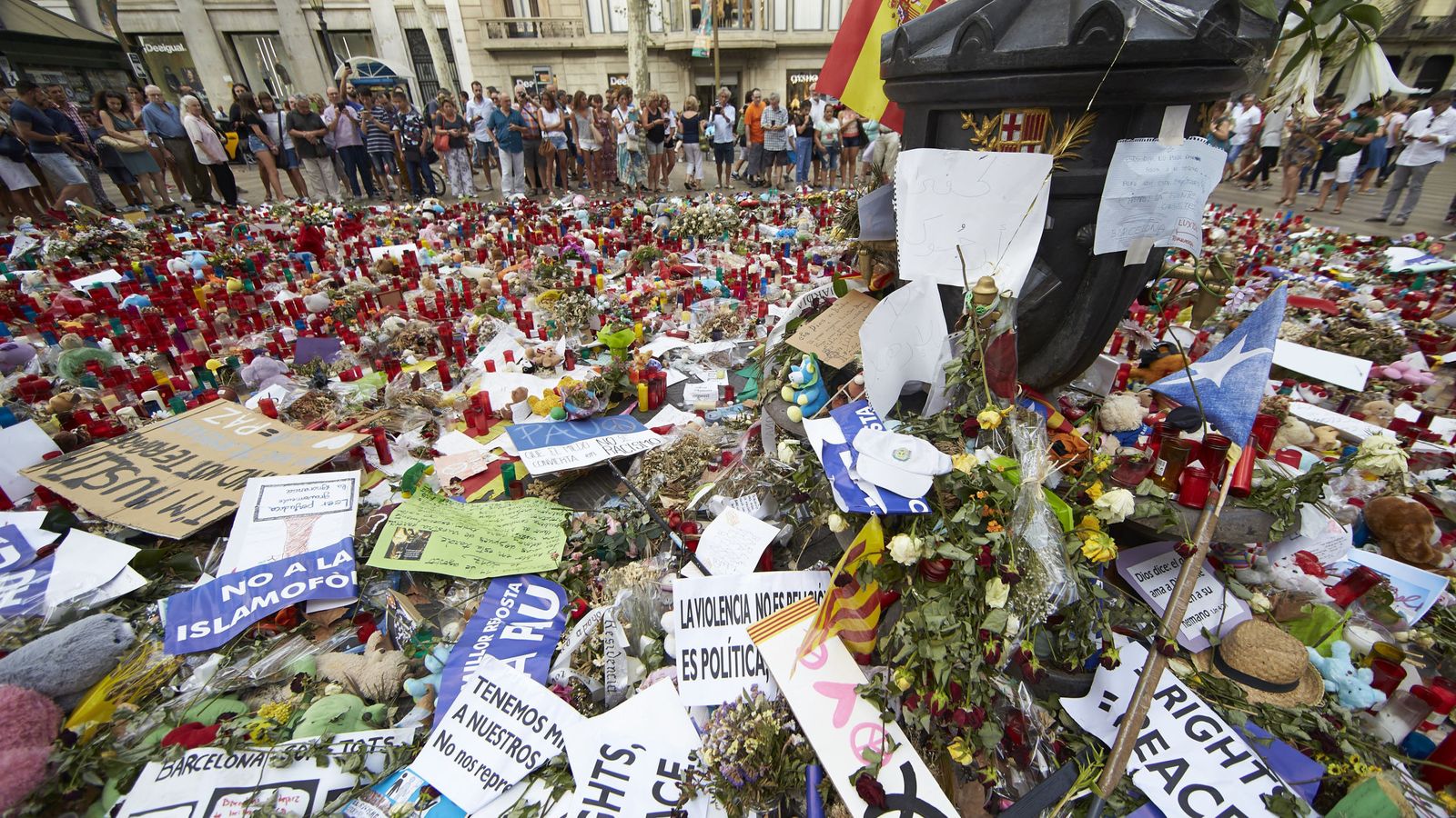 Foto: Ciudadanos y turistas observan los ramos de flores, velas, peluches y dedicatorias a las víctimas del atentado del pasado 17 de agosto. (Efe) 