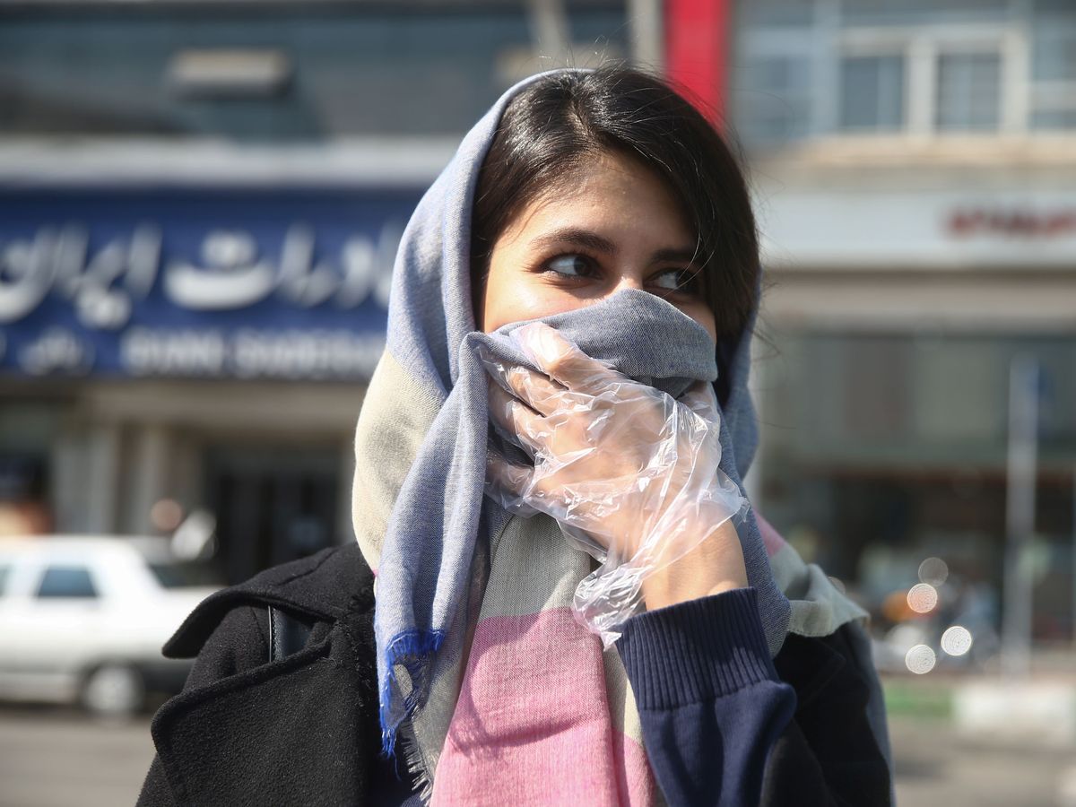 Foto: Una mujer iraní se protege del coronavirus con pañuelo y guantes (REUTERS)