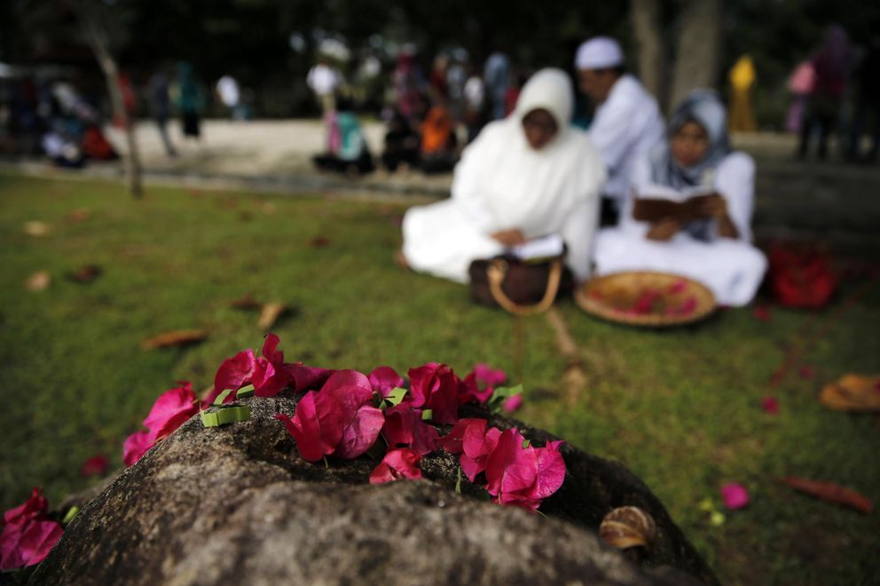 Una familia reza junto a un cementerio para víctimas del tsunami en Banda Aceh (Reuters).