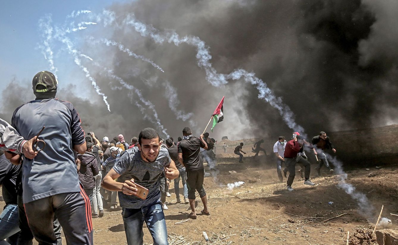 Manifestantes corren para protegerse del gas lacrimógeno lanzado por soldados israelíes durante unas protestas en la frontera de Gaza e Israel, el 14 de mayo de 2018 (EFE).