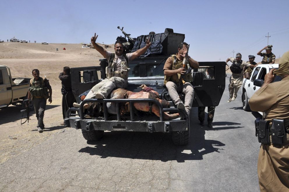 Combatientes kurdos con el cadáver de un yihadista muerto en combates en Yalawla (Reuters).