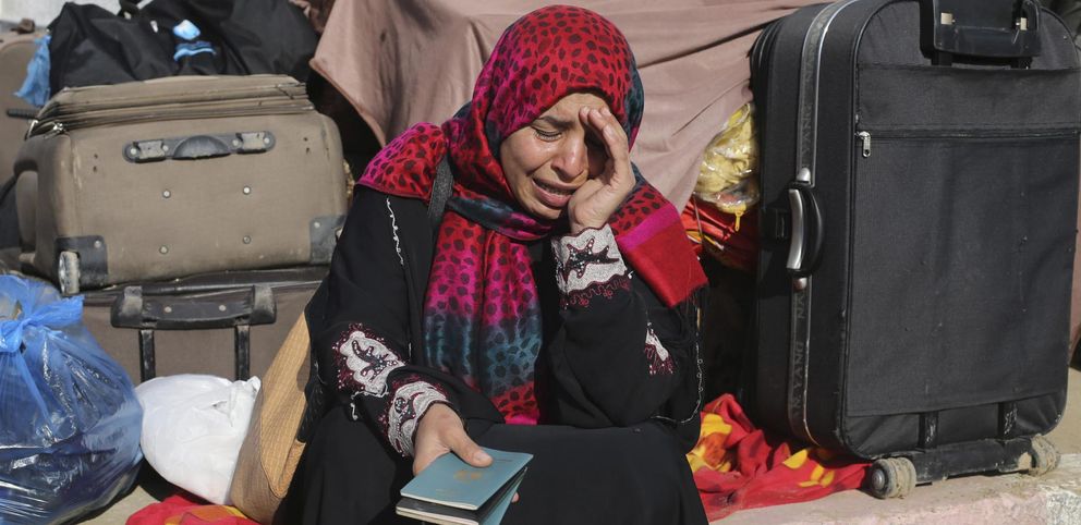 Una mujer llora rodeada de sus pertenencias mientras reza por poder cruzar hasta Egipto (Reuters)