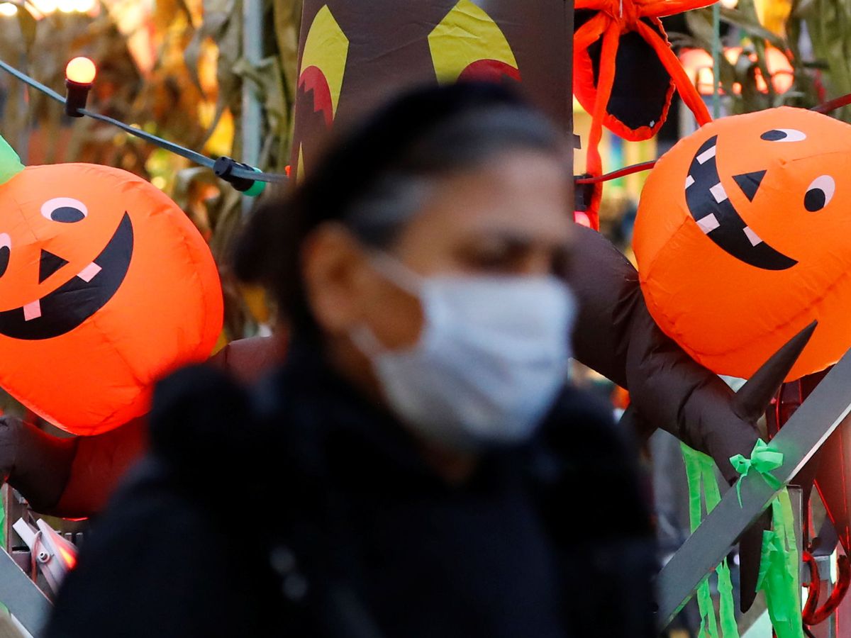 Foto: Mujer con mascarilla con calabazas de Halloween al fondo.