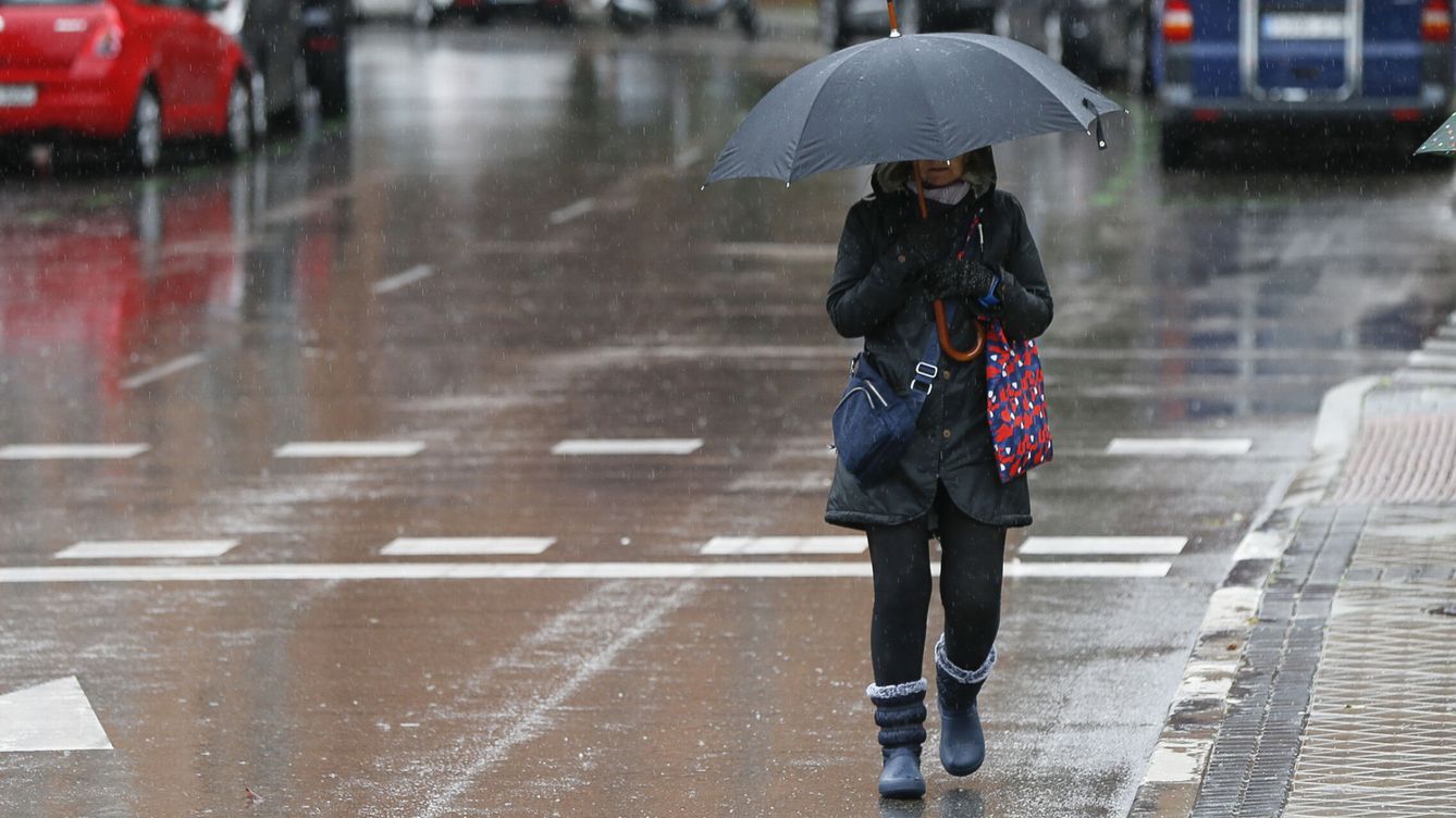 Foto: Una mujer camina bajo la lluvia. (EFE/Víctor Casado)