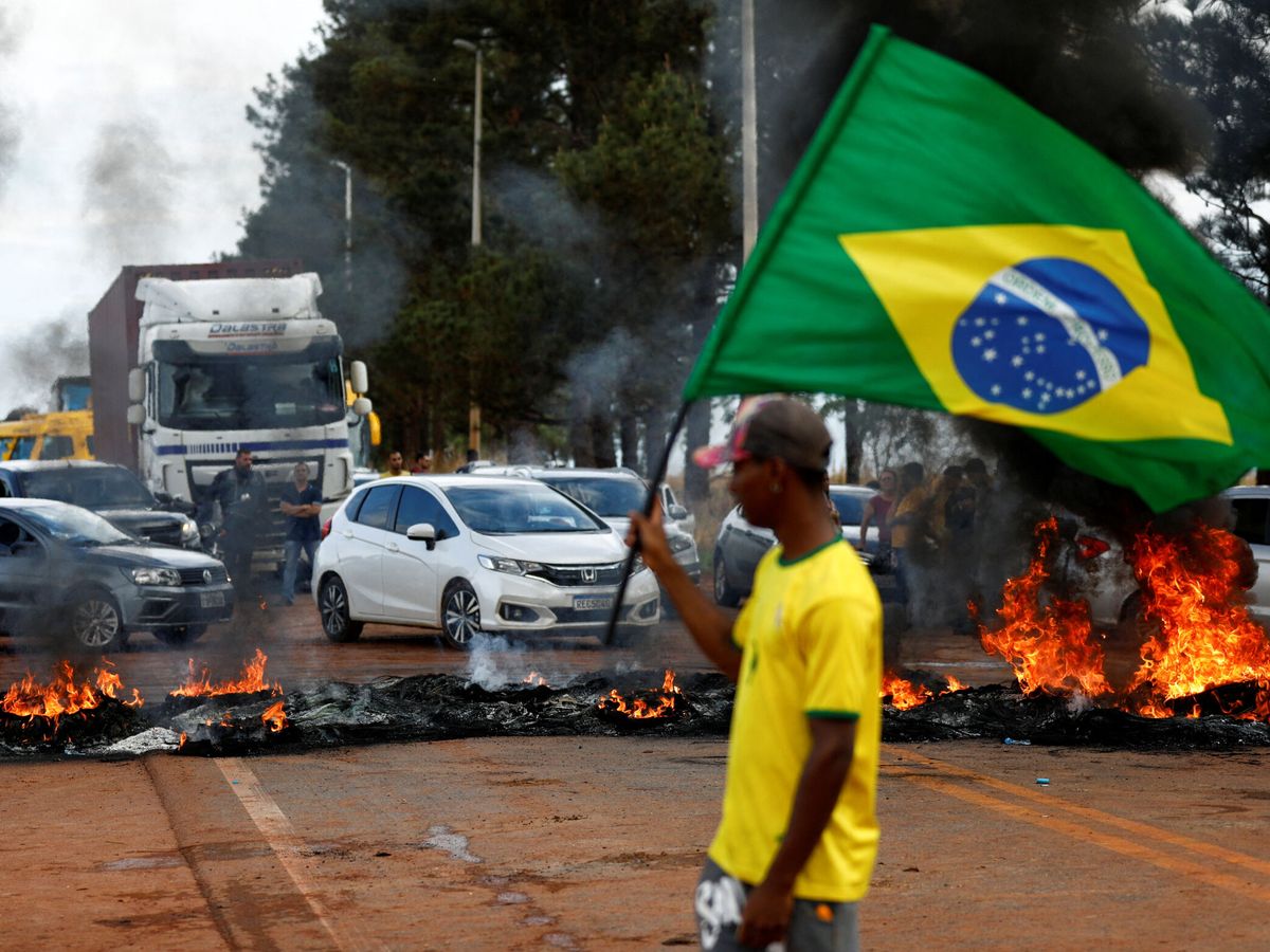 Foto: Un seguidor de Bolsonaro agita la bandera nacional ante el atasco provocado por los simpatizantes. (Reuters/Diego Vara)