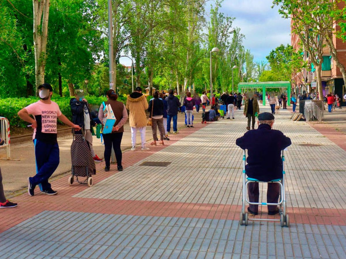 Foto: Cientos de personas hacen cola en el barrio de Aluche para recibir alimentos. (EC)