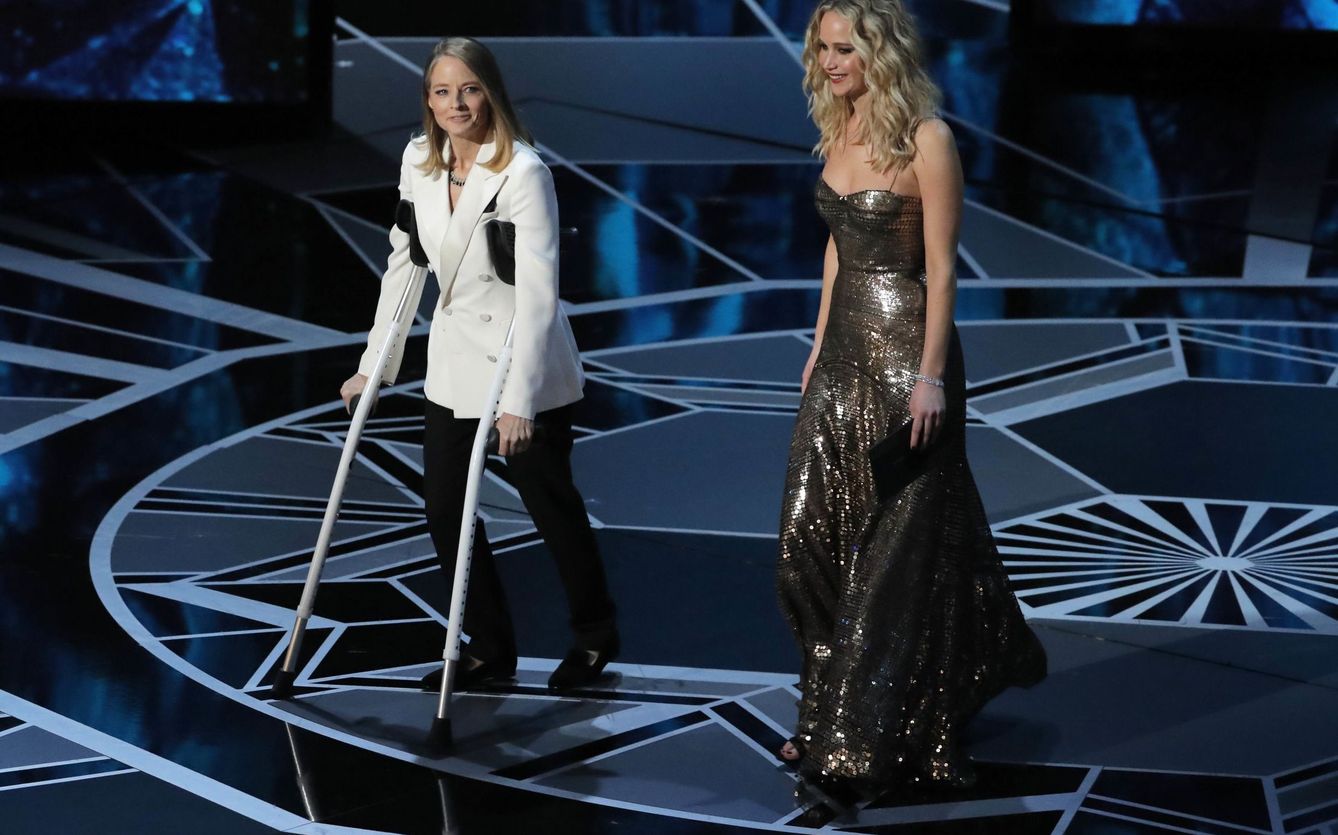 Jodie Foster en muletas junto a Jennifer Lawrence entregan el Oscar a la Mejor Actriz. (Reuters)