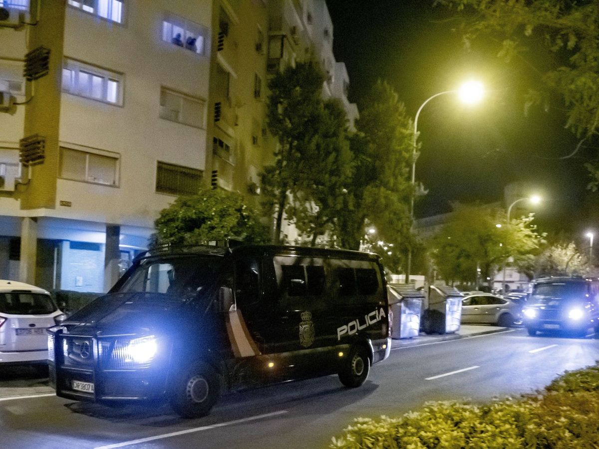 Foto: Dos vehículos de la Policía Nacional patrullan por la calle Amor del barrio sevillano de Amate. (EFE)