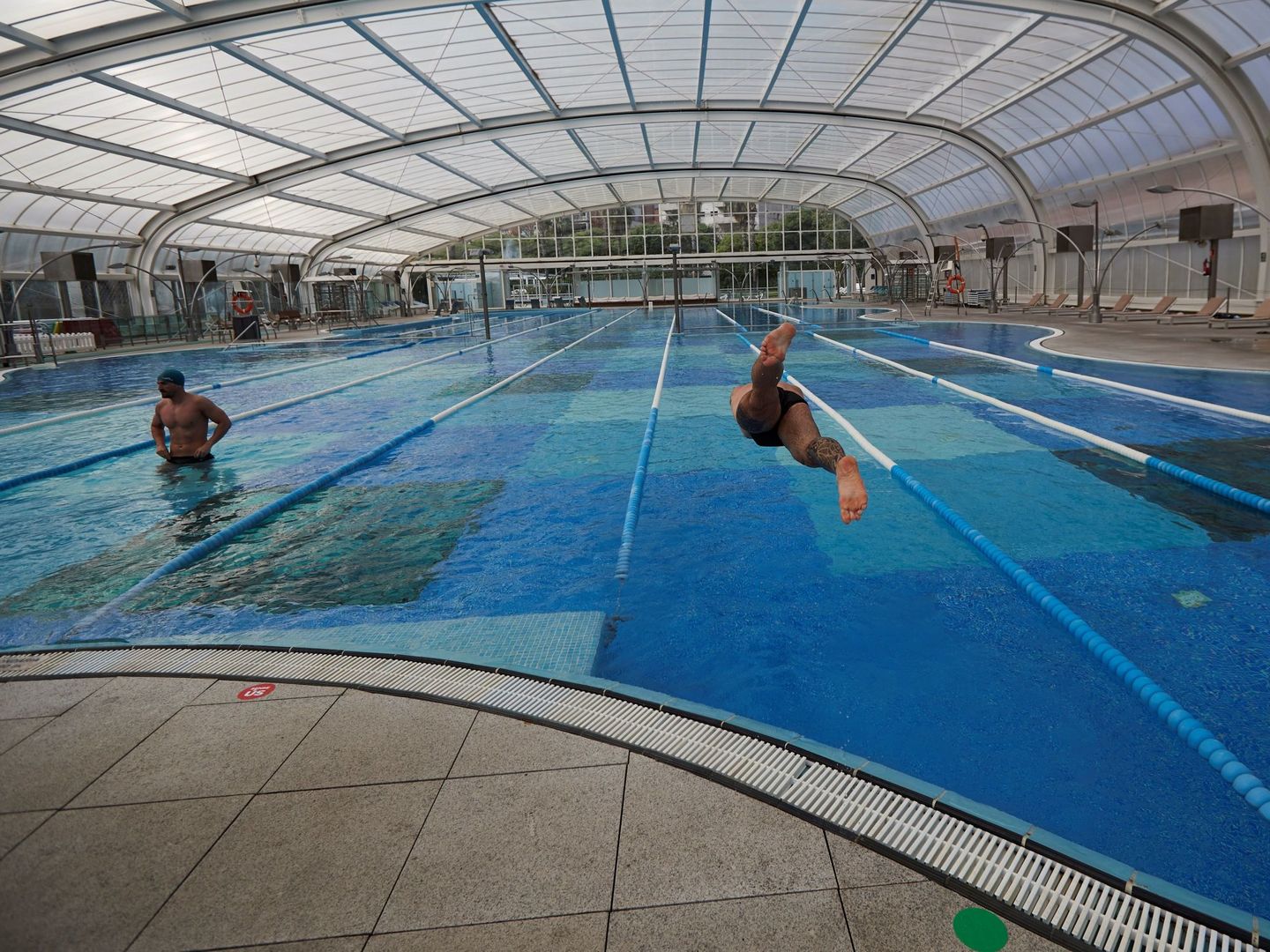 Dos usuarios de una piscina cubierta en Barcelona. (EFE)