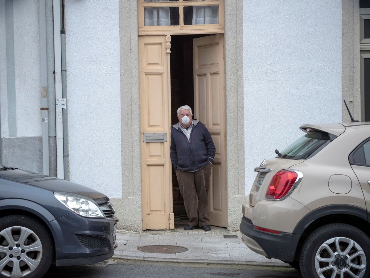 Foto: Un hombre ataviado con mascarilla se asoma a la puerta de su casa en de Palas de Rei, en Lugo, el pasado abril. (EFE)