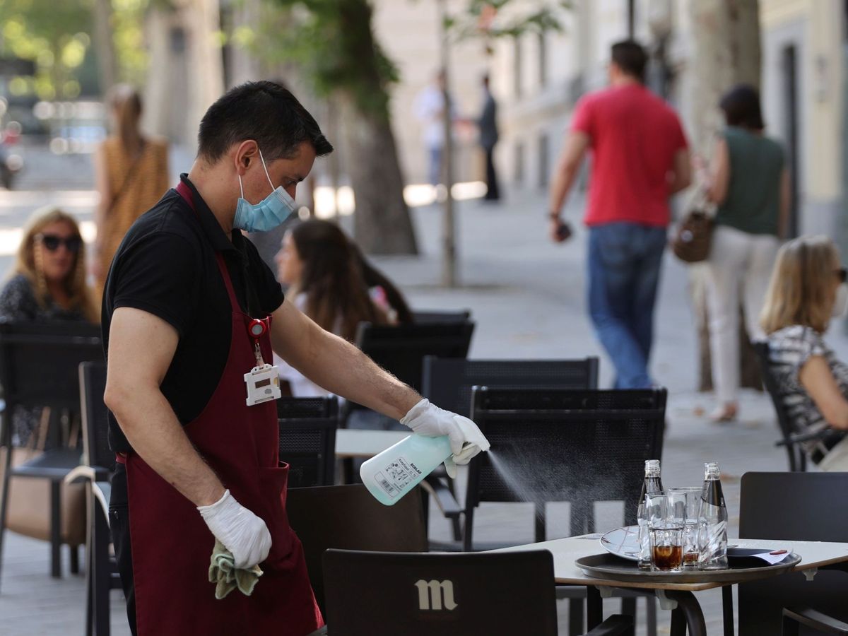 Foto: Un camarero desinfecta una mesa en un bar de Madrid. (EFE)